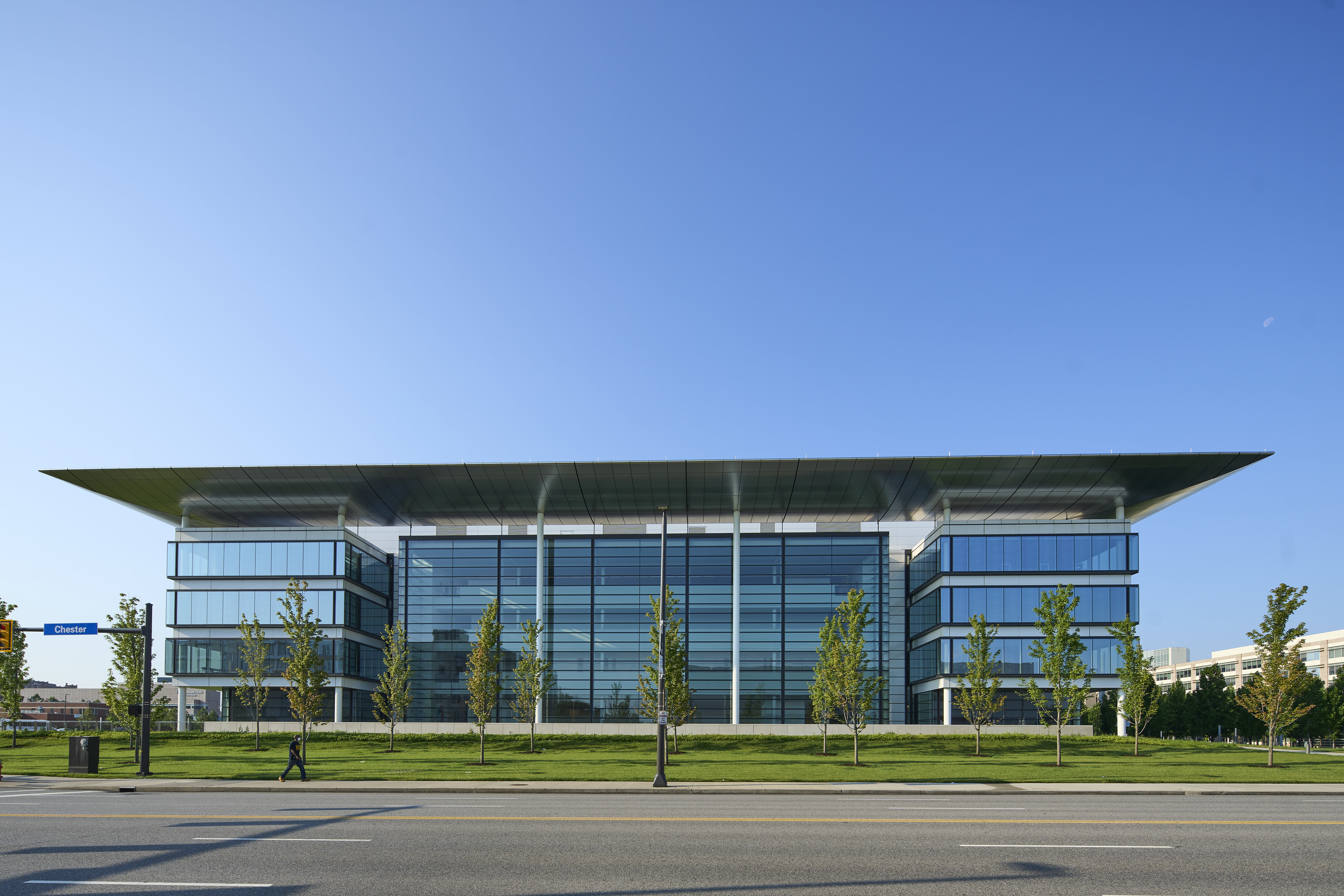 Four story HEC glass building with view of trees and blue skies above